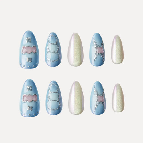 Almond-shaped false nails from the "Blue Frequency" (Park Select) collection, arranged in two rows of five. The set features blue bases with pink bow accents and silver details, blue bases with silver chain patterns, and shimmery pale pink/white solid finishes, showcasing varied nail art designs for application.