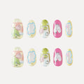 3D press-on nails (Bubblegum Heart collection) with two rows of five medium round nails. Pastel colors (yellow, green, pink) with 3D details: birds, flowers, abstract shapes, glitter, pearls, and text (e.g., "507"). Whimsical, playful designs.