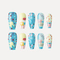 Image of 3D press-on nails from the "Candy Night" collection, featuring coffin-shaped, medium-length nails with vibrant, playful designs. Two rows of five nails each showcase colorful patterns: blue glitter bases with yellow stars and red/pink polka dots; yellow-and-white nails with "LOVE" text and a yellow circular accent; blue nails with abstract pink shapes and red dots; nails with "Los for Paris" text in silver on a blue/pink background; and yellow nails with pink shapes and blue glitter accents.