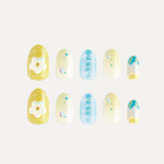 Flat lay of yellow and blue decorative press-on nails with 3D flower charm and gradient patterns.