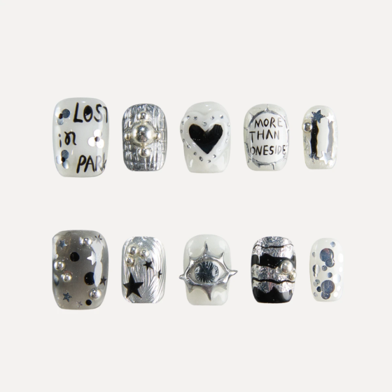 Flat lay of 10 Chrome Vision short square press-on nails featuring silver chrome textures, handwritten text graphics, heart motif, star accents, and 3D metallic studs.