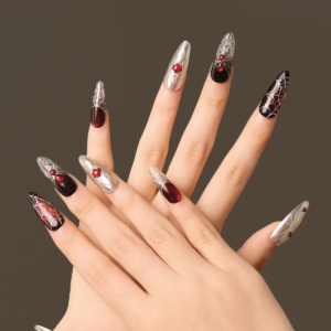 Hands wearing the “Crimson Whisper” long oval press-on nails featuring silver sculpted chrome textures, black-red ombré accents, and spiderweb details.