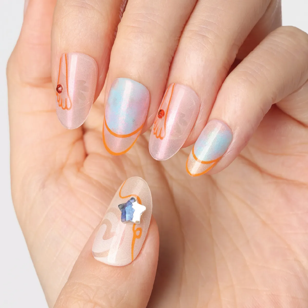 Detailed view of “Crystal Mist” press-on nails showing pearlescent blue-pink gradients, orange contour lines, and a star-shaped crystal charm on the thumb.