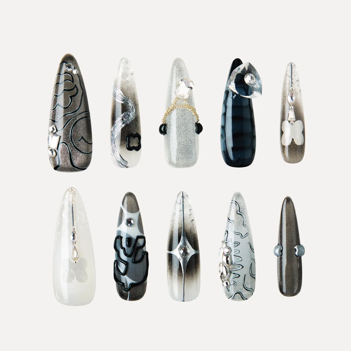 Flat lay of Cyber Pulse long stiletto press-on nails arranged in rows with metallic gradients, chrome 3D pieces, and futuristic black-silver designs