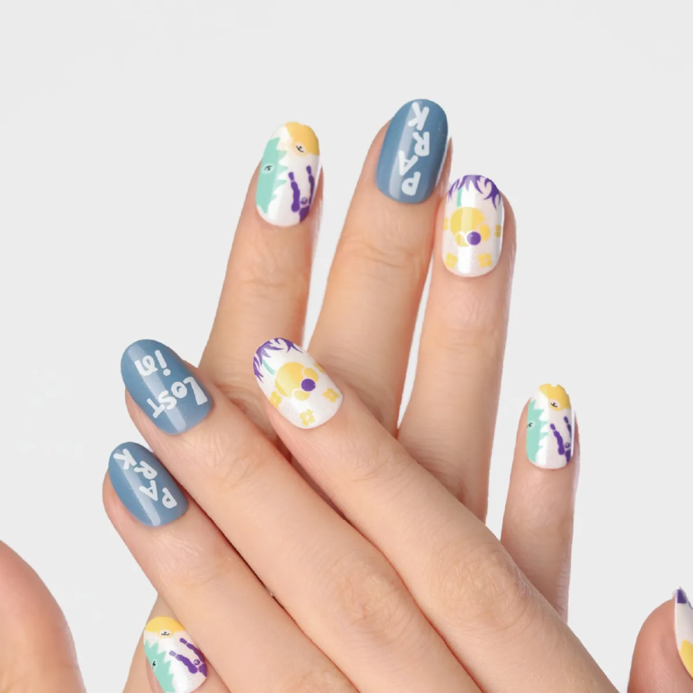 Hand pose showcasing Day Dreaming press-on nails with mix of floral prints, doodle-style graphics, and blue text designs
