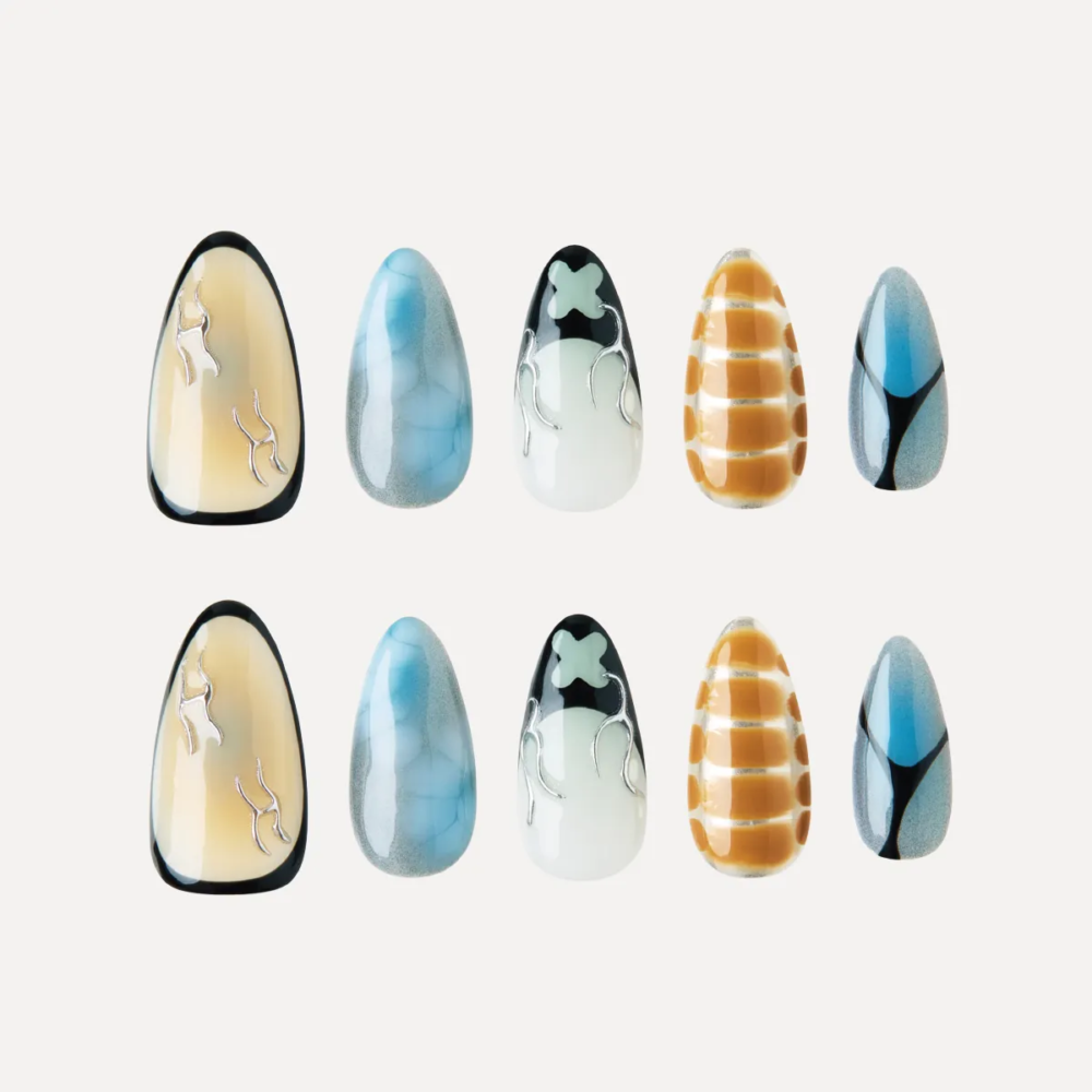 product_lost-in-park-Deconstruct-Vision-press-on-nails Flat lay of Deconstruct Vision press-on nail tips featuring abstract lines, smoky blue textures, yellow grid print, and black-white flame motifs