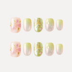 Flat lay of Dewy Garden press-on nail tips featuring pink roses, green floral embossing, and shimmering gradient designs