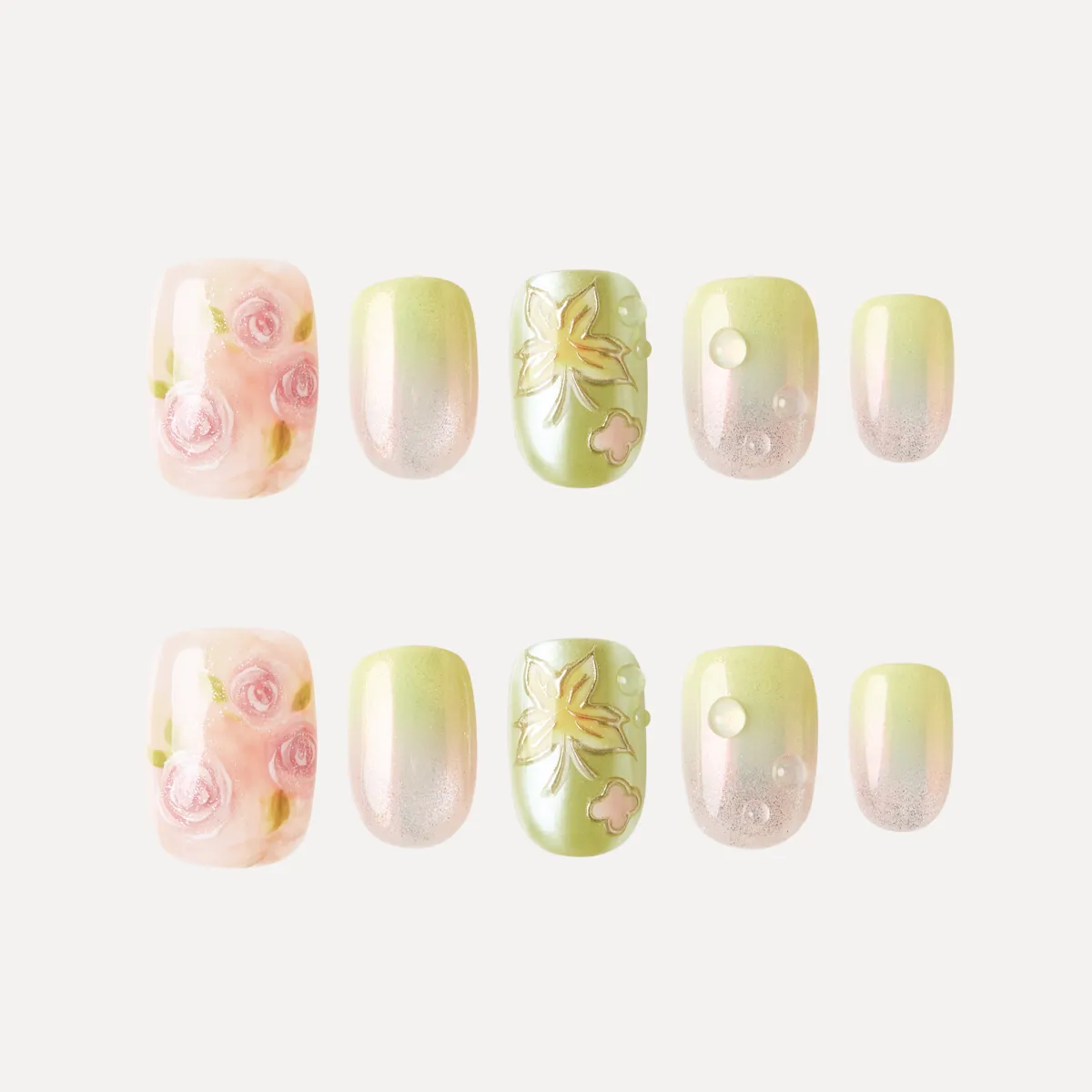 Flat lay of Dewy Garden press-on nail tips featuring pink roses, green floral embossing, and shimmering gradient designs