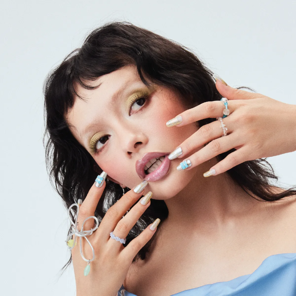 Model wearing Digital Galaxy press-on nails in silver, gold, and blue with futuristic graphic designs