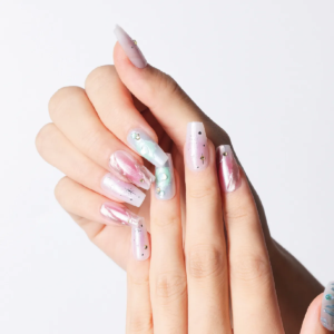 Hand wearing iridescent pink and blue press-on nails with starburst and pearl accents