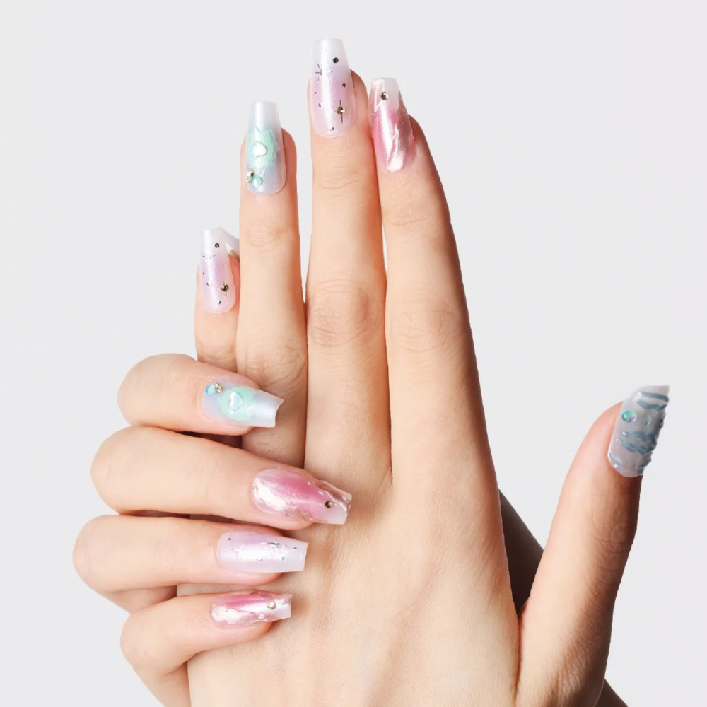 Hand showing pastel galaxy-inspired press-on nails with shimmer and 3D pearl details