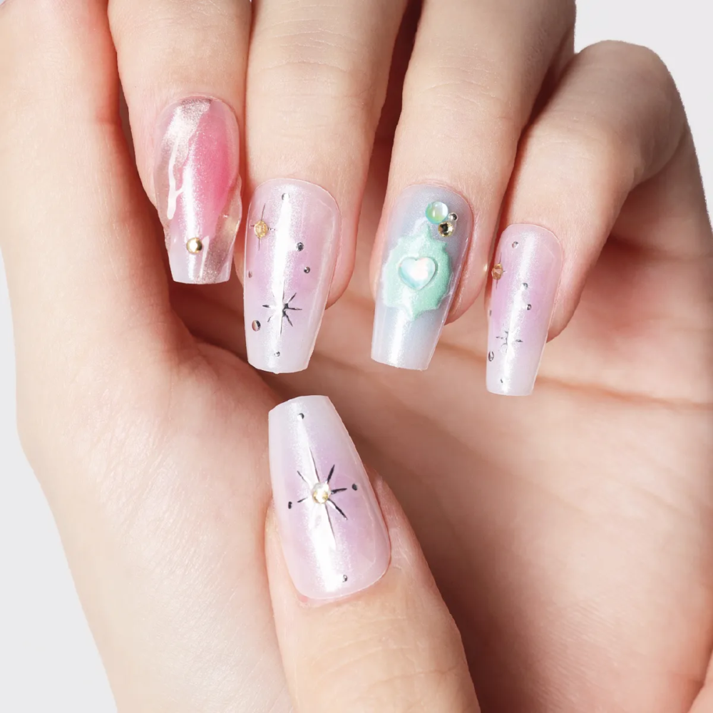 Close-up of galaxy-themed press-on nails with pink chrome, star details, and mint 3D heart design