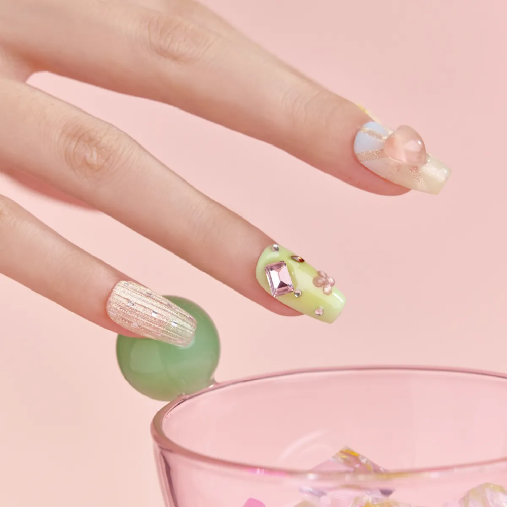 Close-up of pastel green and pink gemstone press-on nails with textured glitter accent