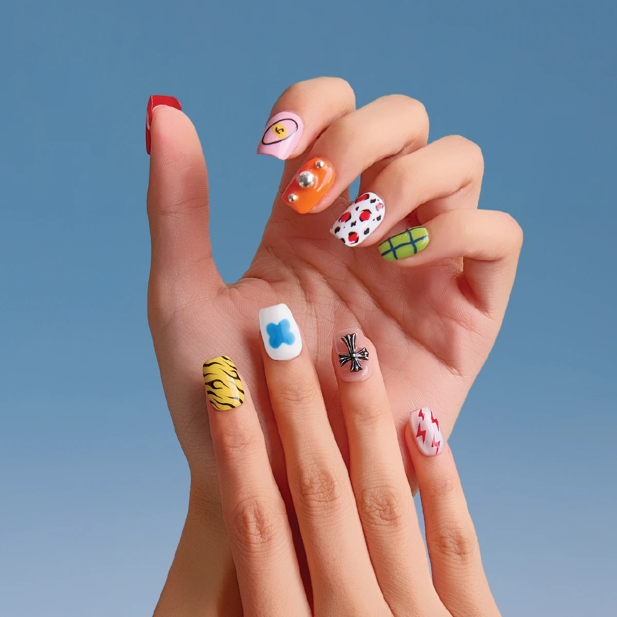 Hand wearing colorful short square press-on nails with playful pop art designs