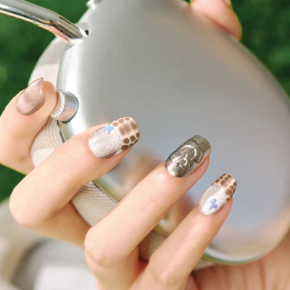 Close-up of “Mocha Mirage” nail design – shimmer, giraffe pattern, blue flower accent