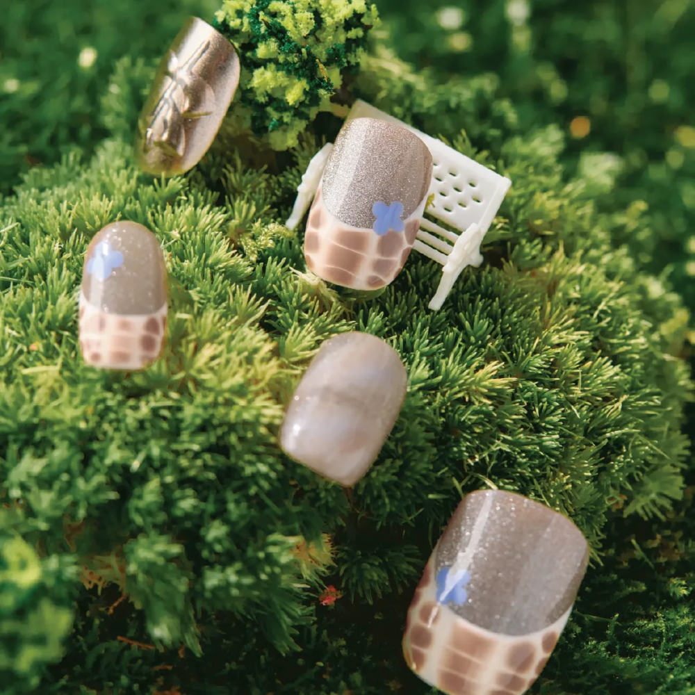 Mocha Mirage press-on nails displayed on grass with mini chair props