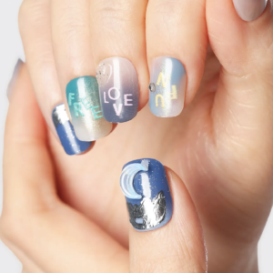 Macro shot showing moon and angel motif on thumb with colorful letter details on other nails