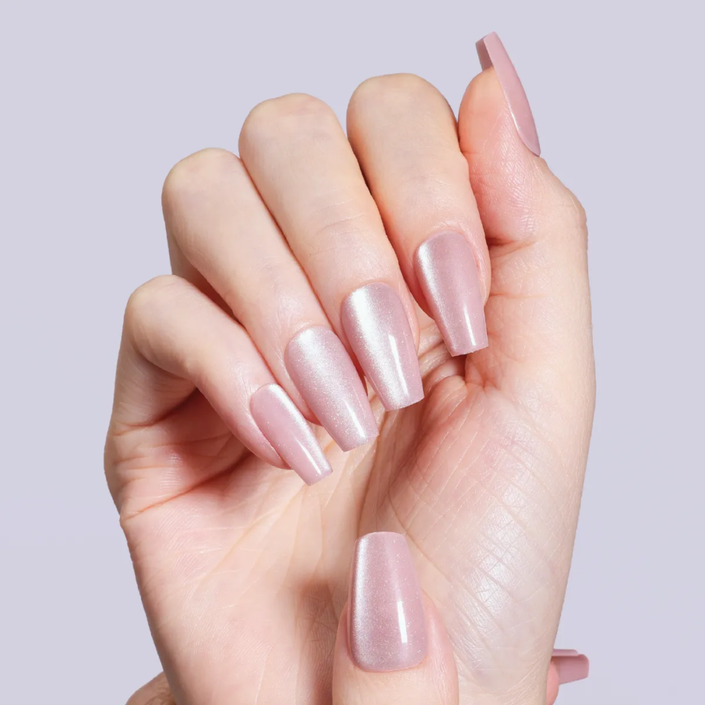 Model hand wearing LOST in PARK Pearl Glass press-on nails with pearly pink shimmer in coffin shape