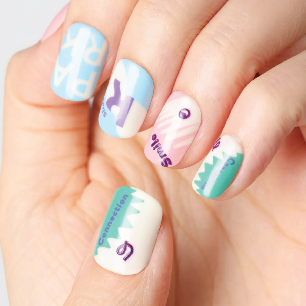 Close-up view of pastel nail details with words like "Smile", "Connection" and graphic accents