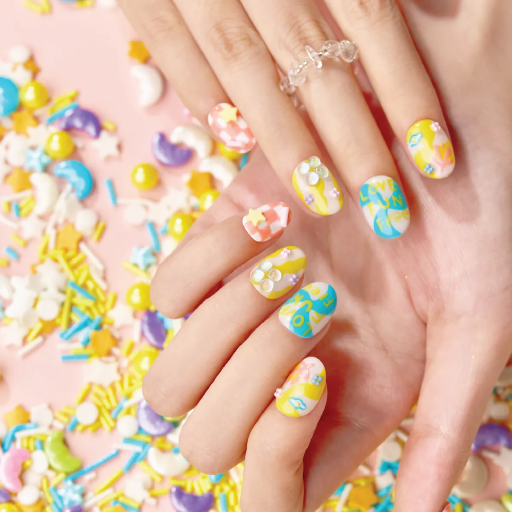 Model hand wearing LOST in PARK Starlight Bubble press-on nails in playful candy colors with star and pearl accents.