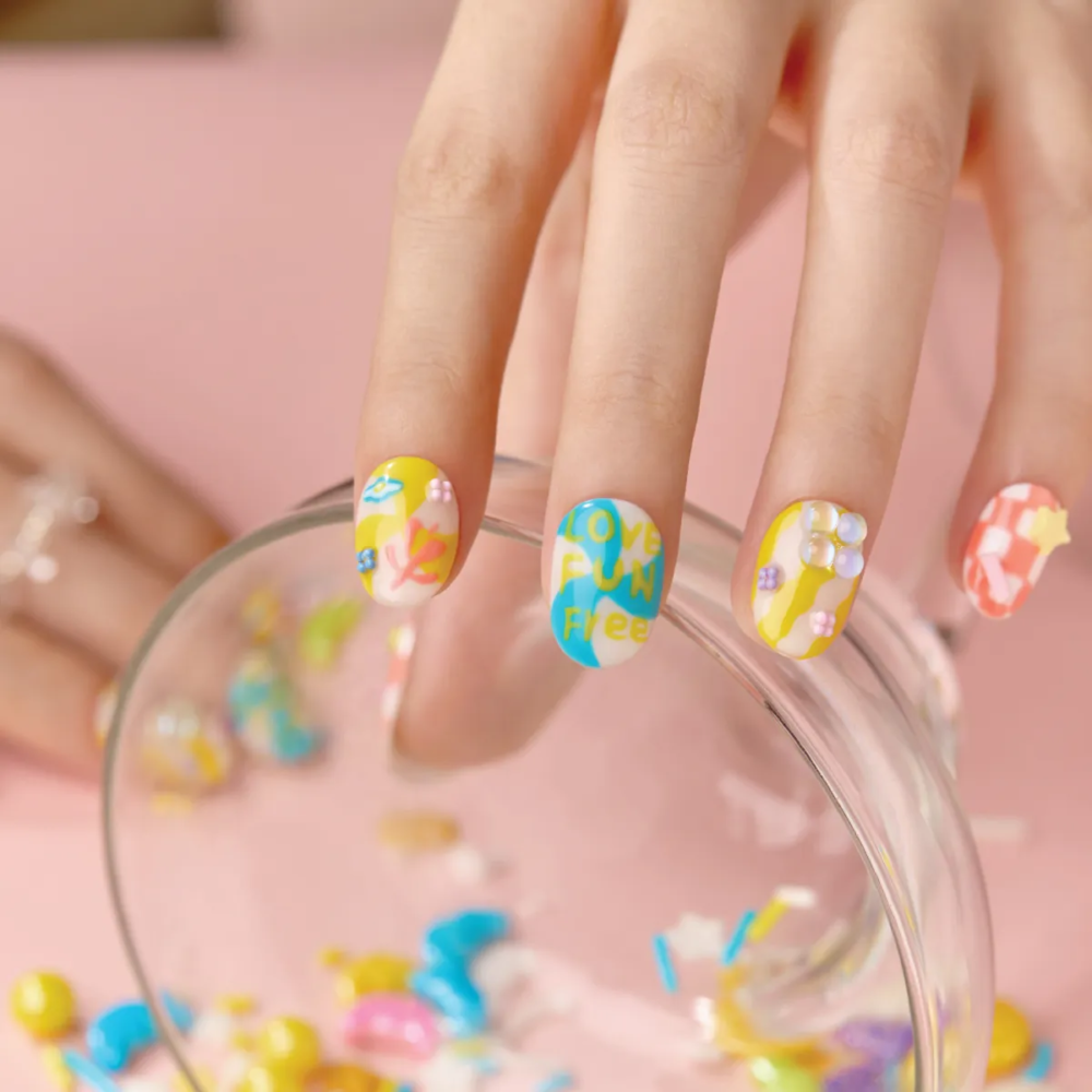 Model hand wearing LOST in PARK Sweet Dream Bomb press-on nails in playful candy colors with star and pearl accents.