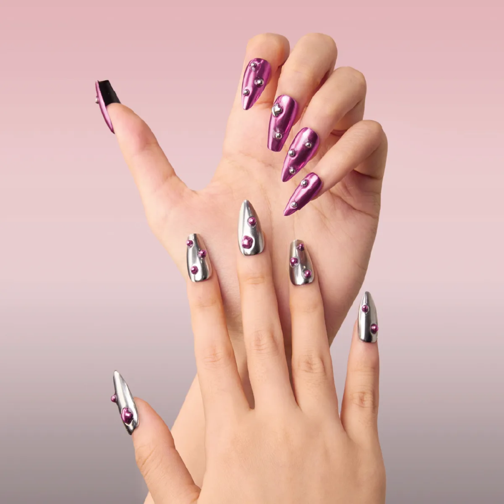 ands wearing chrome press-on nails in alternating pink and silver, styled on pink gradient background
