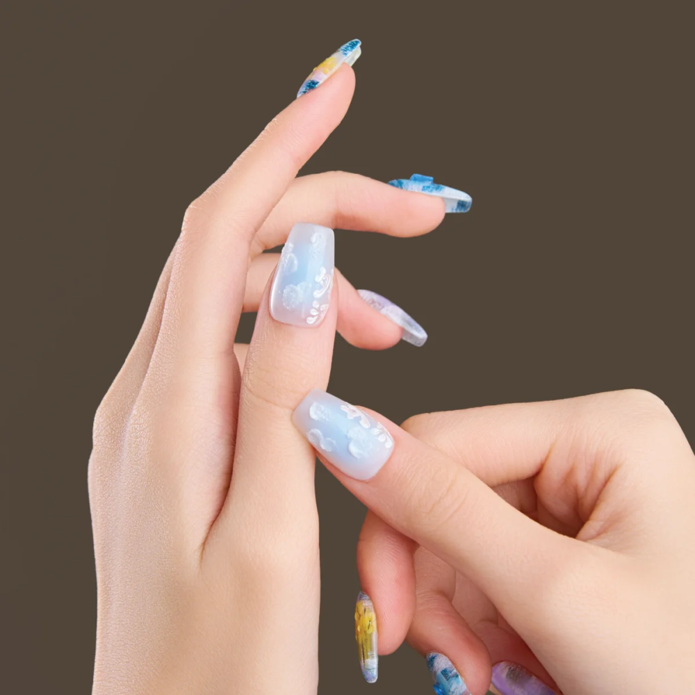 Medium coffin press-on nails photographed on hand with soft translucent finish and artistic color layers