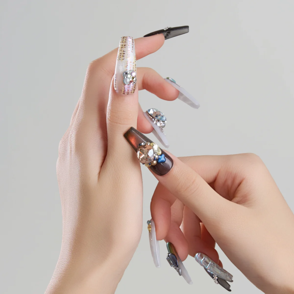 Close up of long coffin press on nails with gemstones chrome details and graphic text elements