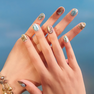 Short round press-on nails with green, gold and amber tones on hands