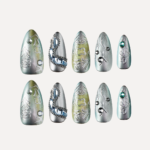 Medium almond press on nails flat lay in silver green tones with embossed patterns chains and gemstone details