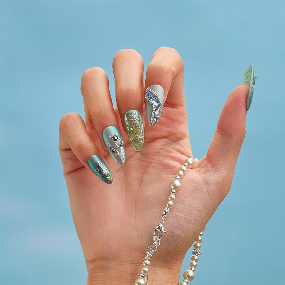 Back view of hands wearing medium almond press on nails with jewelry inspired design